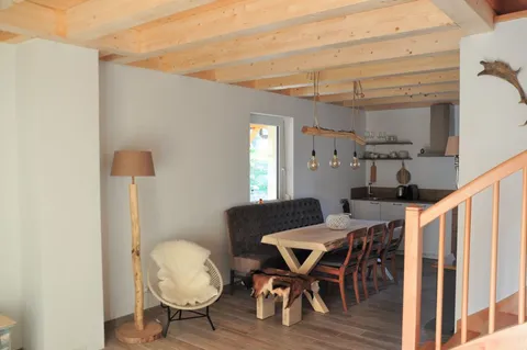 Eethoek met houten tafel en open keuken op de achtergrond