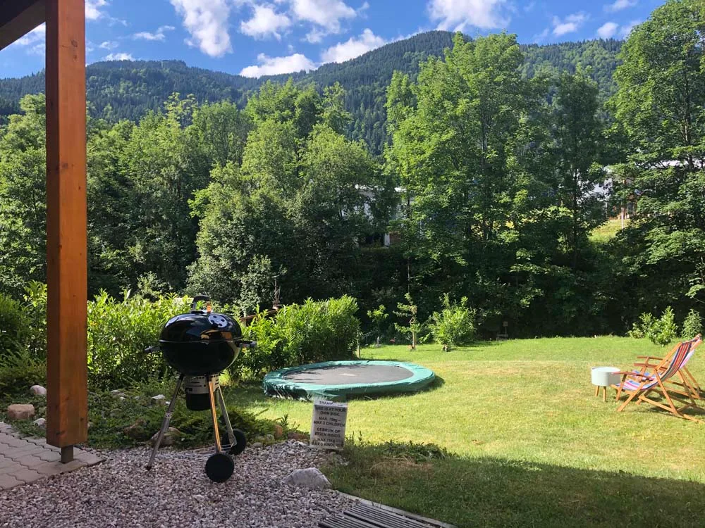 Achtertuin met trampoline en ligstoel, met uitzicht op de bergen